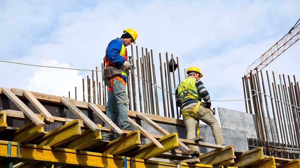 Construction site workers reinforcing concrete with rebar for building development.